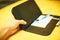 Selective focus customer hand receive bill payment receipt in black leather folder holder tray on yellow wooden table background