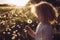 Selective focus cute blonde curly hair girl blowing blossomed dandelion flower head  seedlings fly away.