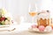 Selective focus of delicious Easter cake decorated with meringue with pink and white eggs on plate near wine glass and