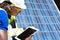 Selective focus at digital tablet. African and Caucasian engineer inspect electrical solar panel and record information into