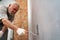 selective focus. an elderly man paints the metal garage door with a roller.