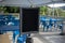 Selective focus on an empty black sign in front of a reserved seating area filled with blue chairs under an outdoor canopy