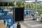 Selective focus on an empty black sign in front of a reserved seating area filled with blue chairs under an outdoor canopy