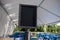 Selective focus on an empty black sign in front of a reserved seating area filled with blue chairs under an outdoor canopy