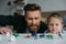 selective focus of father and cute little son looking at arranged toy dinosaurs on tabletop together