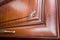 Selective focus fragment of cherry alder wooden cabinetry kitchen carved detail. Wooden pilasters. Decor furniture