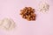 Selective focus on a handful of raw organic almond nuts on a pink background, near scattered sesame seeds and oat-flakes