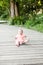 Selective focus of Happy 6 month little kid wearing pink dress crawling on the grass and playing