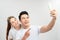 Selective focus of happy asian couple taking selfie on smartphone isolated on white