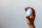 selective focus male hand stained with blue paint holding a freshly painted Easter egg against a white wall with place