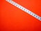 Selective focus.Measuring tape on a red background.Shot were noise and film grain.