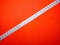 Selective focus.Measuring tape on a red background.Shot were noise and film grain.