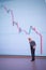 Selective focus miniature figurine businessman looking down - crude oil price crash with out of focus downward chart in the backgr