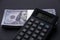 Selective focus of money and calculator with word DEBT on a black background