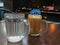 Selective focus with noise effect of glass with fresh water and tea with milk or popularly known as Teh Tarik