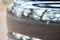 Selective focus on parking sensor of parking assistent system at rear of luxurious car bumper close up on light blurred background