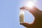 Selective focus on person hand holding glass jar full of small white round homeopathy pills.