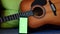 Selective focus on phone with greenscreen of chromakey mockup with tracking markers near the guitar with copy space.