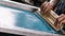 Selective focus photo of male hands with squeegee. serigraphy production. printing images on t-shirts by silkscreen method