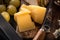 Selective focus of pieces of cheese and knife on cutting board next to grapes on tray.