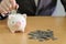 Selective focus piggy bank coin with stack of coin on wooden desk and business men with financial protection action. Saving money