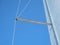 Selective focus of the poles and white fabric of a boat sail against a blue cloudy sky