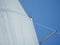 Selective focus of the poles and white fabric of a boat sail against a blue sky