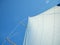 Selective focus of the poles and white fabric of a boat sail against a blue sky