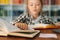 Selective focus of pretty pupil school girl kid doing homework reading paper book sitting at table in children room.