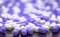 Selective focus purple and white capsule pills on stainless steel drug tray. Pile of capsule pills. Pharmaceutical industry.