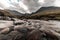 Selective focus of the rocky rushing stream of the waterfall surrounded by hills in The Isle of Skye