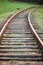 Selective focus rounding of railway abandoned rusty, overgrown with grass and moss. Empty turning single track of