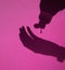 Selective focus of a shadow of hands pouring hydroalcoholic disinfectant gel for the prevention of Covid19 on a pink background