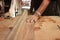 Selective focus and shallow depth of field. Front view of a piece of wood is being shaved on a router table by hands of carpenter