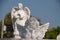 Selective focus shot of a baby angel statue with a blurred female angel statue background