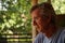 Selective focus shot of a Caucasian older man sitting outdoors on a sunny day with a worried look