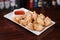 Selective focus shot of crispy fried wontons with a sauce on a wooden table
