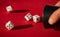 Selective focus shot of dices falling out of the dice shaker on a red surface