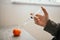 Selective focus shot of a hand with a syringe injected into a mandarin