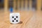 Selective focus shot of the number five on a white dice on a wooden surface with blurred background
