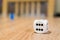 Selective focus shot of the number six on a white dice on a wooden surface with blurred background