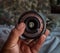 Selective focus shot of a photograph hand holding a camera lens
