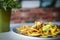 Selective focus shot of a plate of nachos with sauce on a white table near a plant