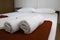 Selective focus shot of rolled towels arranged on a neat white bed with a blurred background