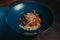 Selective focus shot of spaghetti bolognese in dark blue plate