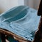Selective focus shot of washed blue bed linen on the old wooden chair