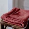 Selective focus shot of washed red bed linen on the old wooden chair