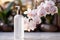 Selective focus on skincare bottle with blooming orchid background