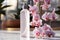 Selective focus on skincare bottle with blooming orchid background