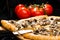 selective focus on sliced piece of appetizing Italian cheese pizza with marinated mushrooms on wooden board on dark background